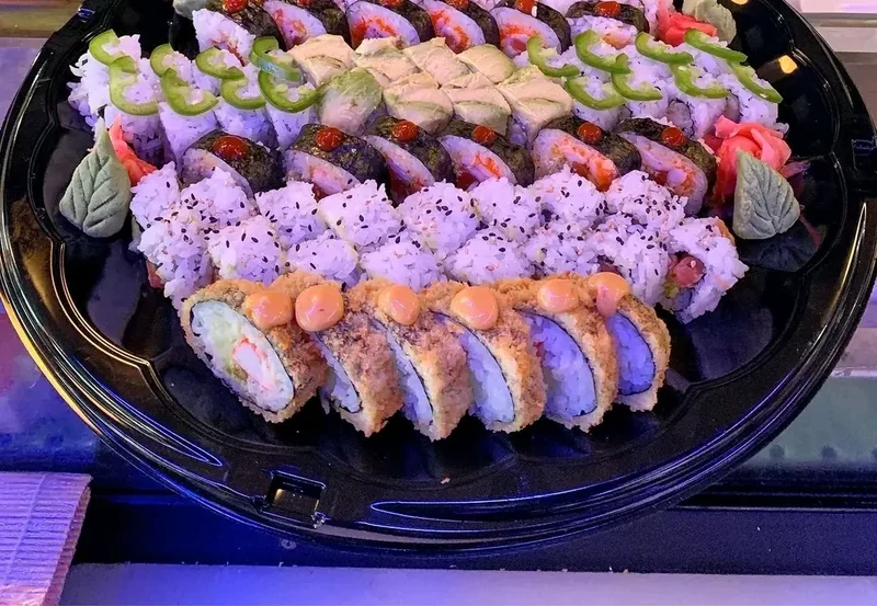 Round catering platter packed with sushi rolls topped with jalapeño slices and crisp panko