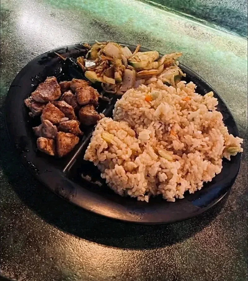 Plate of hibachi steak bites with fried rice and grilled vegetables