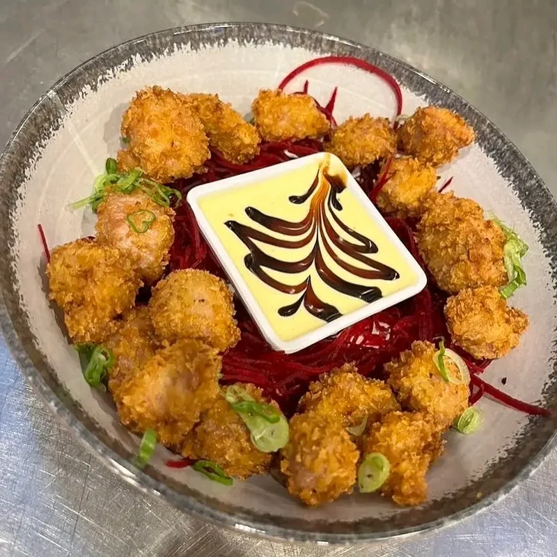 Panko fried shrimp arranged over beet noodles with yuzu aioli in a glass bowl