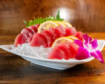 Plate of thick-cut raw tuna sashimi with shiso leaf and shredded daikon