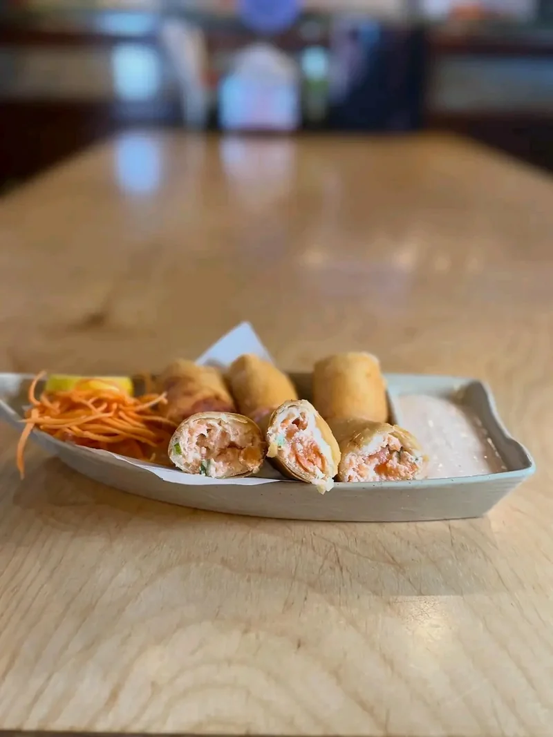 Salmon and cream cheese egg rolls cut and plated on a white boat dish