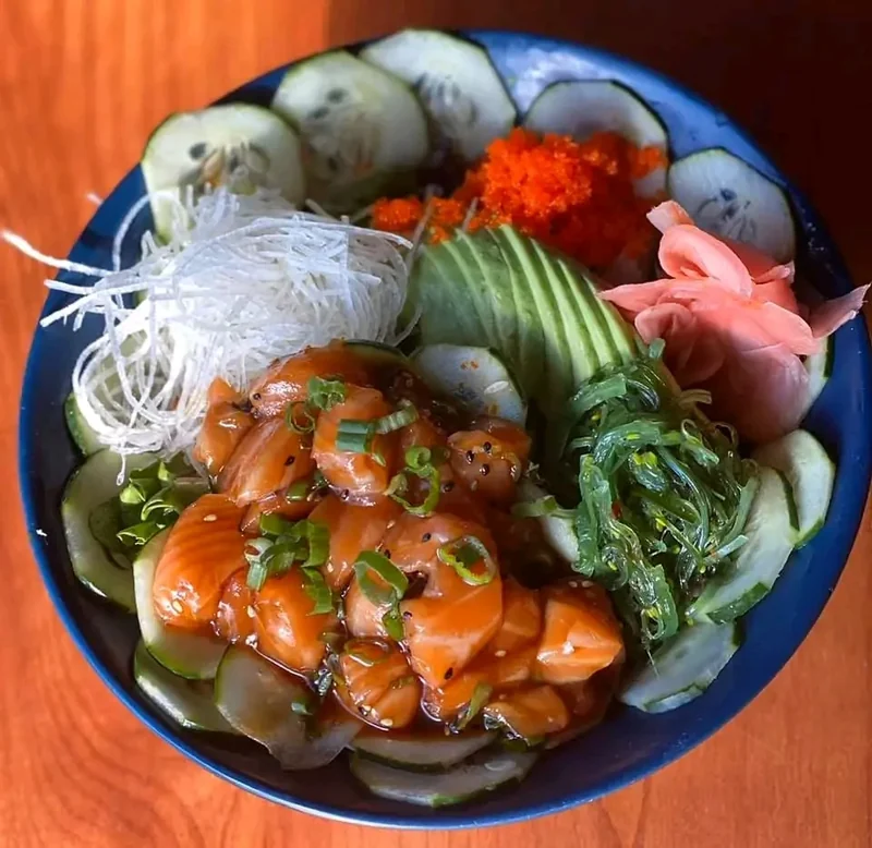 Salmon poke bowl with cucumber, sliced avocado, seaweed salad, tobiko and pickled ginger