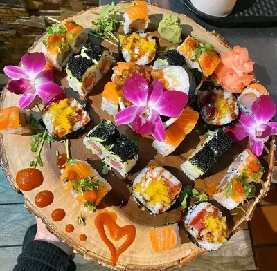 Sushi platter on a round live-edge wood board decorated with orchids